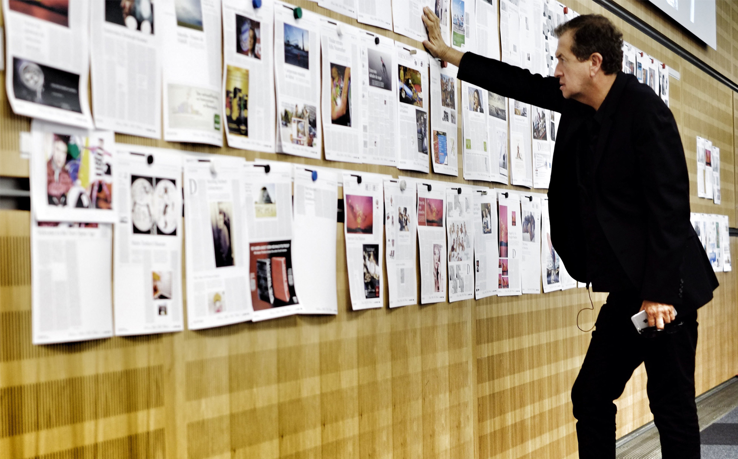 Mario Testino reviewing a magazine pagination on a wall.