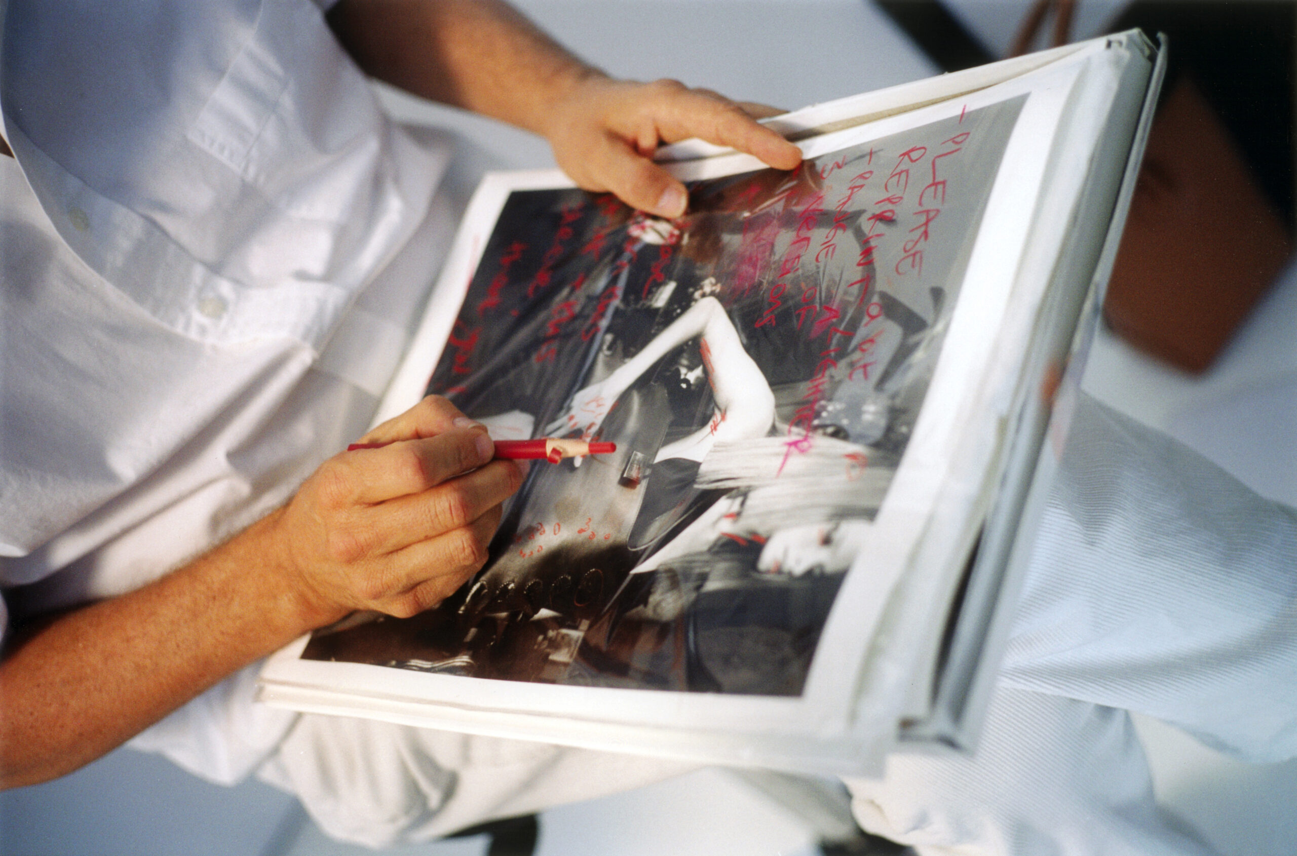 Mario Testino reviewing and marking up a printed image.